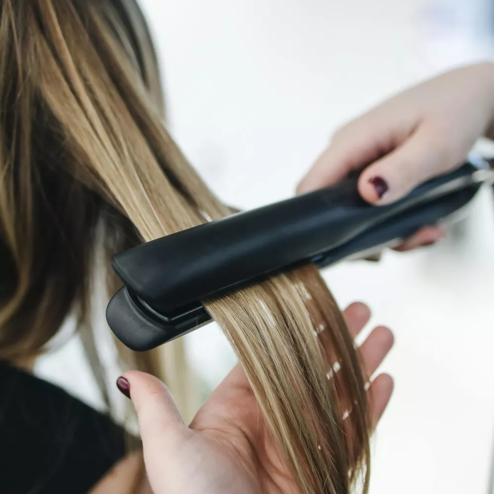 un hairstylist usa una piastra per capelli perfettamente pulita
