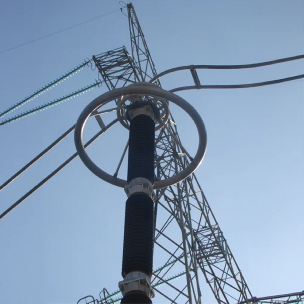 Close-up view of a high-voltage electrical component and transmission tower against a clear sky.