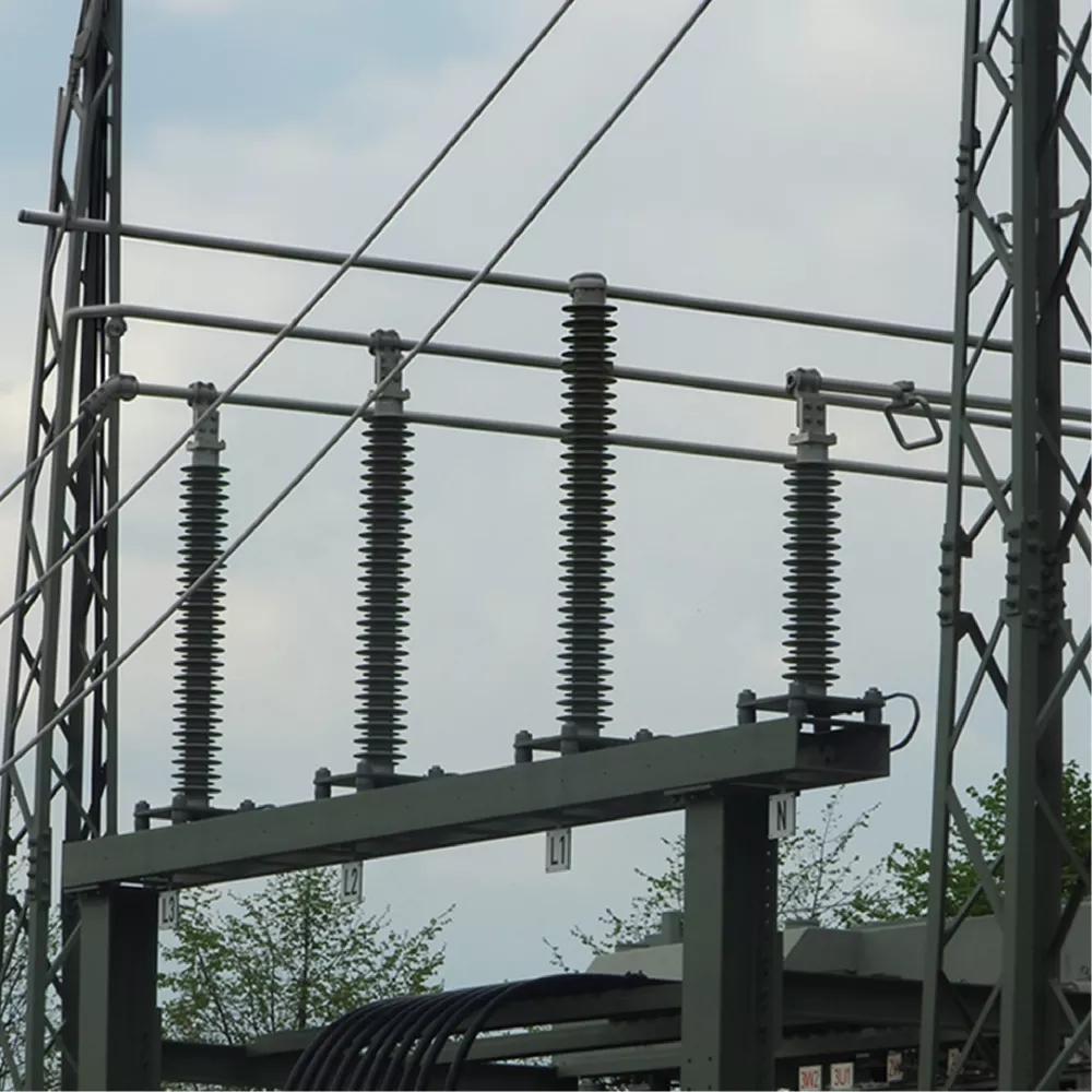 High-voltage electrical insulators and power lines mounted on a metal structure outdoors.