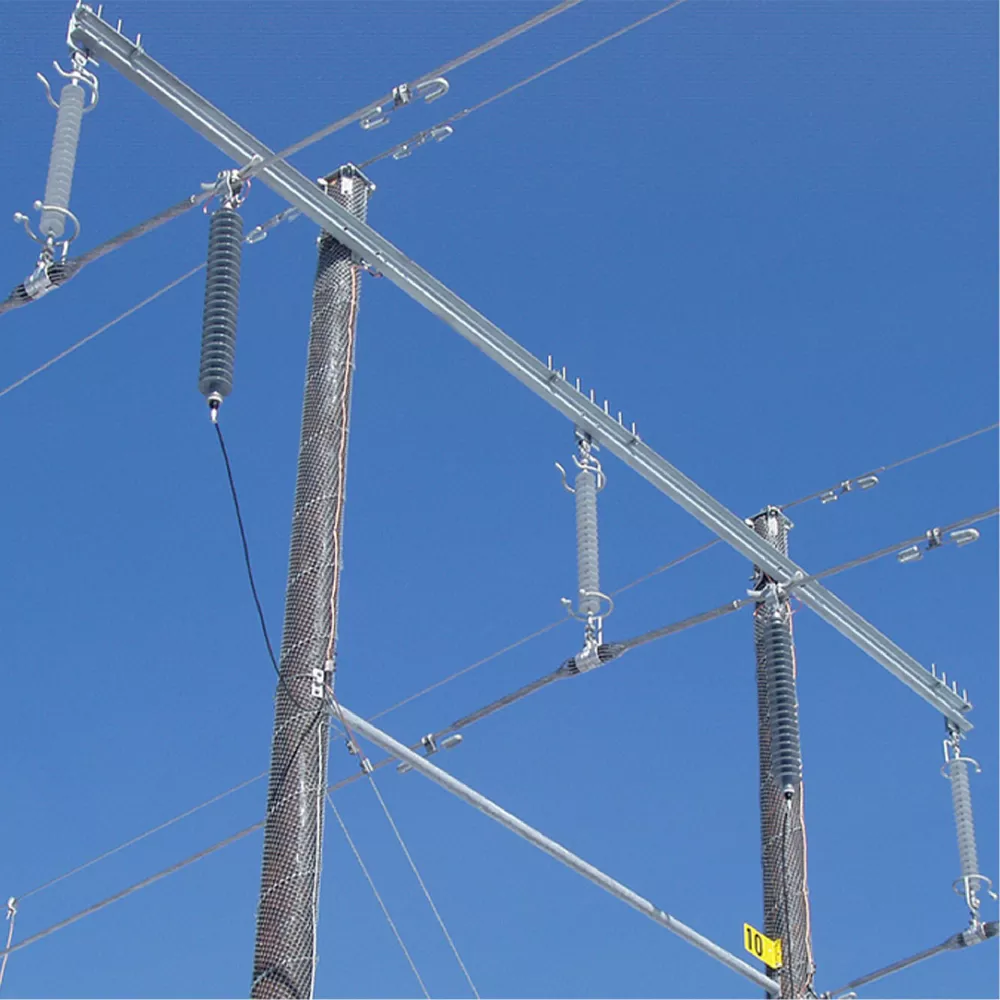High-voltage power line insulators and cables mounted on utility poles against a blue sky.