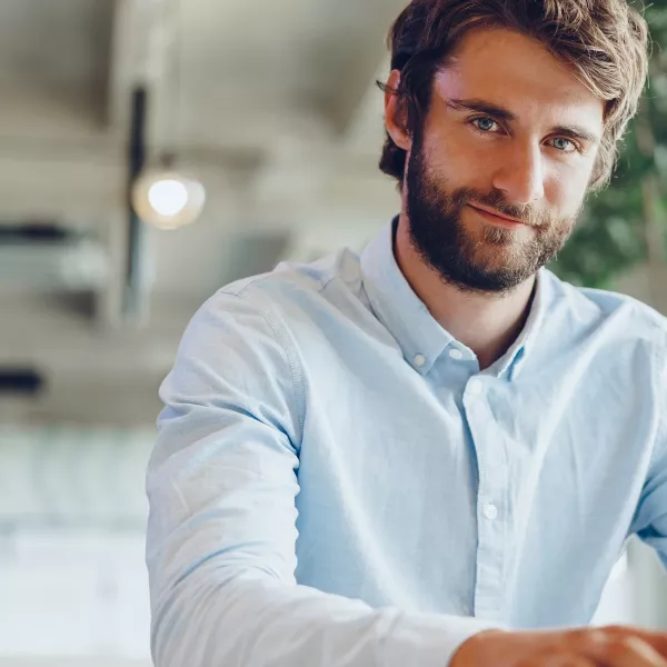 Mann im hellblauen Hemd am Laptop im modernen Büro mit Pflanzen – digitales Arbeiten.