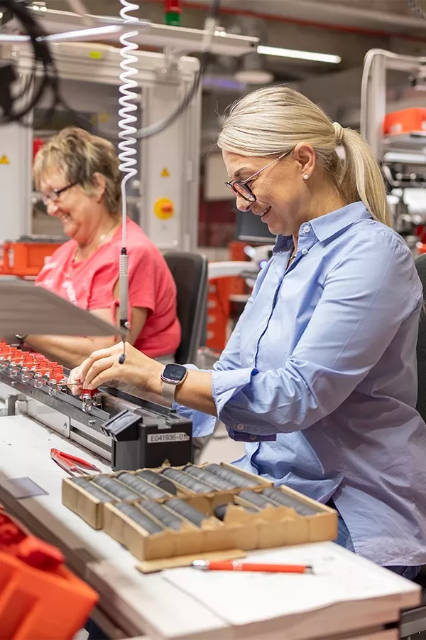 Zwei Personen arbeiten an Maschinen in einer Werkstatt.